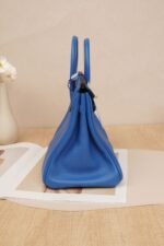 Side view of a Hermès Birkin 25 bag in Bleu Brume Togo leather with gold hardware