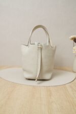 Side view of Hermès Picotin Lock 18 bag in Nata Clemence leather with gold hardware and ostrich leather handle